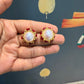 krivoya Devnavi pearl stud earrings featuring a central white pearl surrounded by small red stones in gold setting