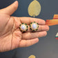 krivoya Devnavi pearl stud earrings featuring a central iridescent pearl surrounded by green stones in gold settings